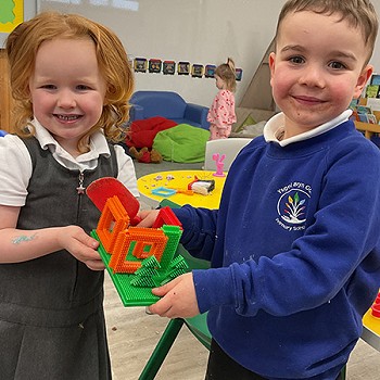 Two children holding a model they built together in the classroom